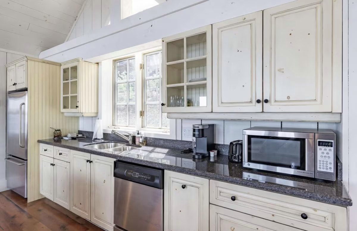 Boathouse kitchenette with cream cabinets, granite counters, and a lake window
