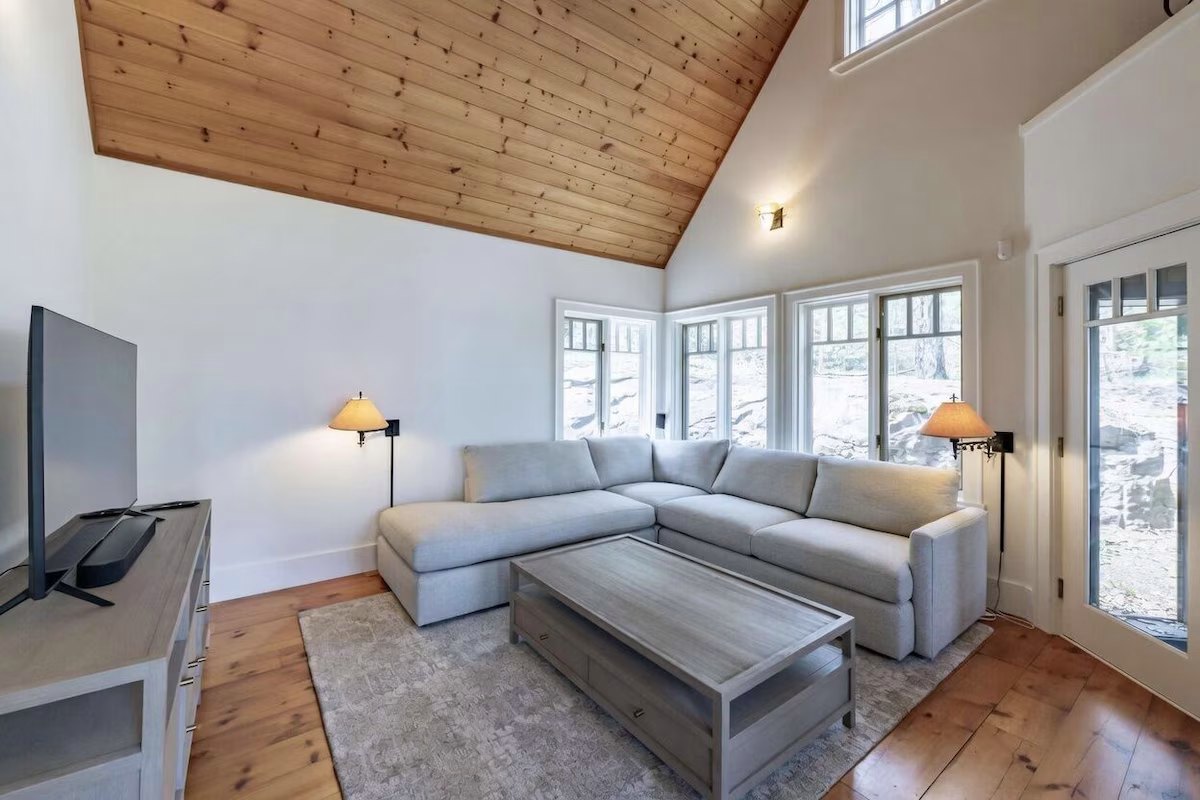 Den with a grey sectional, pine floors, and windows onto the granite