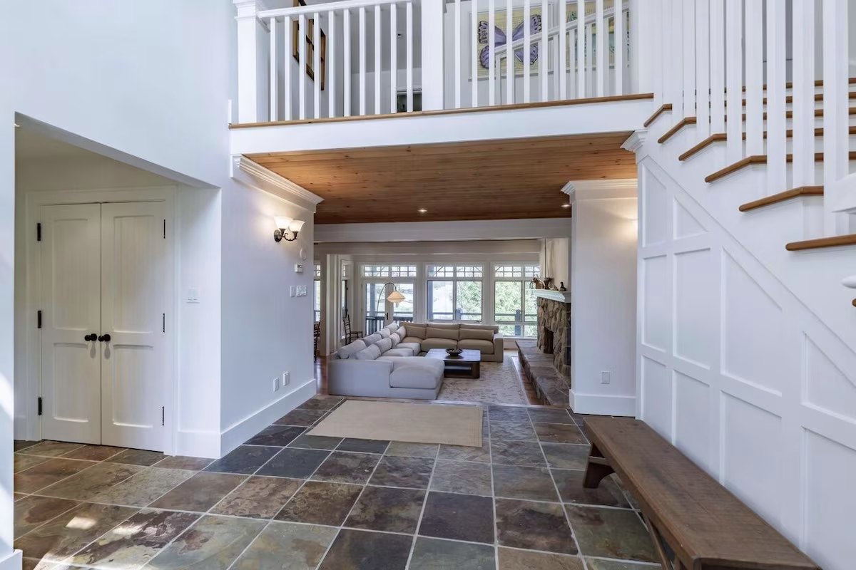 Front hall looking through to the great room — slate floor, stone fireplace, and lake windows