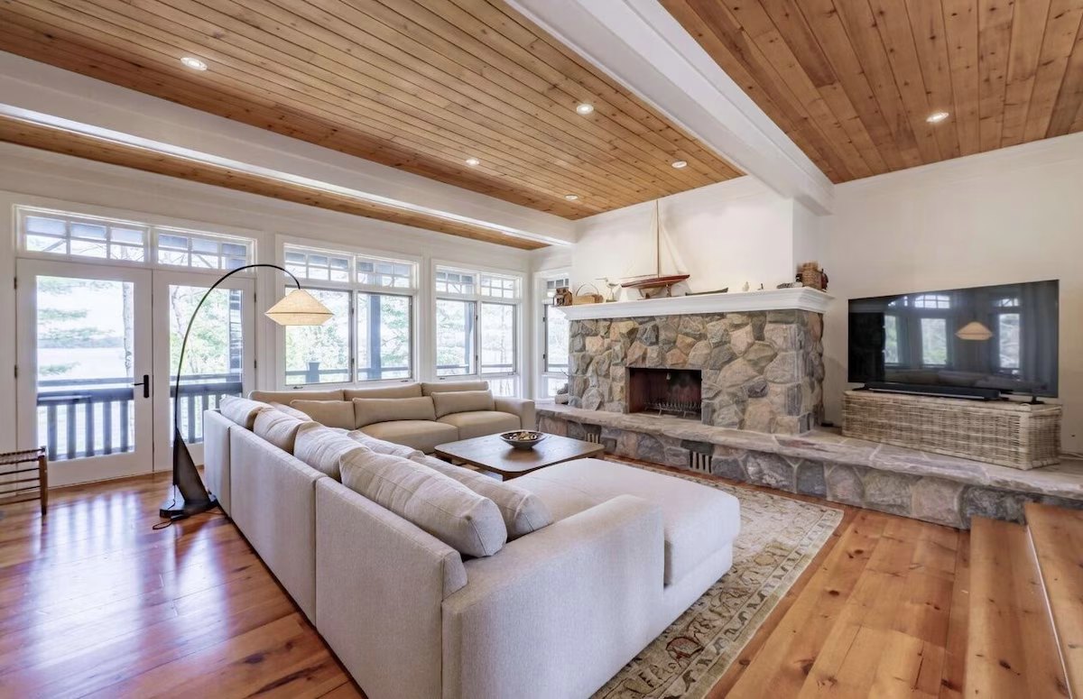 Living room looking at the stone fireplace, model sailboat, and lake windows