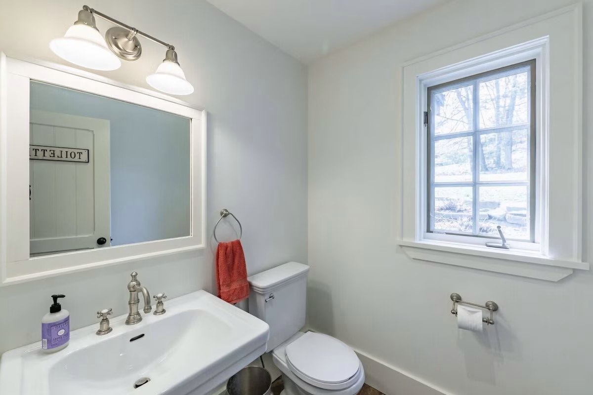 Powder room with a white pedestal sink and a window onto the trees
