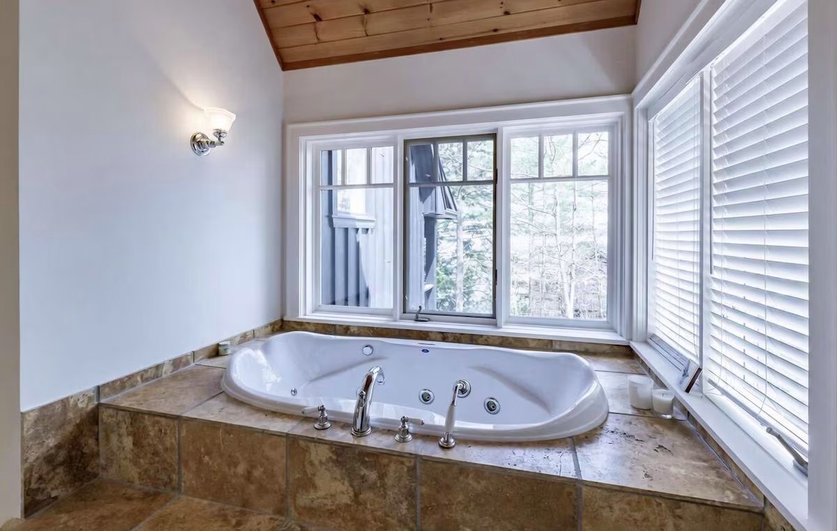 Soaking tub in the primary ensuite with a view through the trees