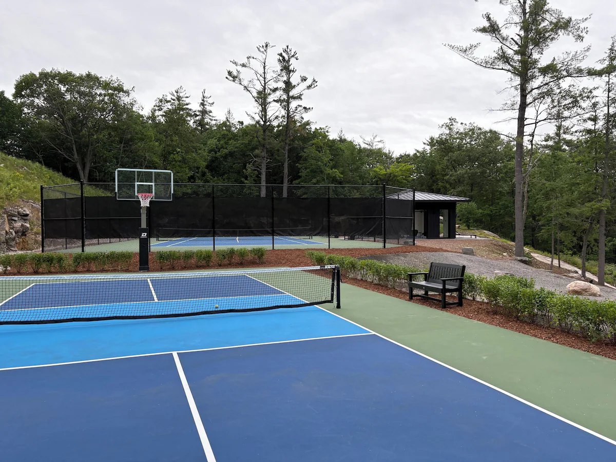 Dedicated pickleball court with a basketball hoop and a second court beyond
