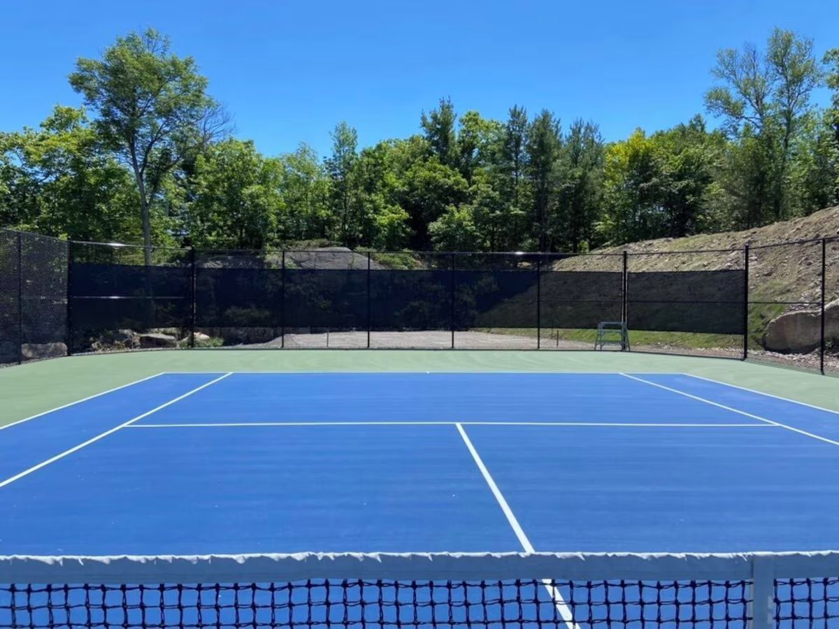 Private tennis court from the net, pines and a rock cut beyond